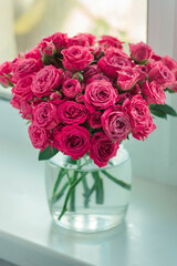 A chic bouquet of small pink roses in a jar on the windowsill. Cute still life 