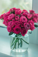 A chic bouquet of small pink roses in a jar on the windowsill. Cute still life 