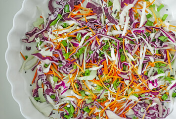 Coleslaw cabbage salad with cabbage, carrots, herbs and sesame seeds on a white plate. Healthy eating, vegan food