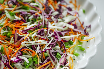 Coleslaw cabbage salad with cabbage, carrots, herbs and sesame seeds on a white plate. Healthy eating, vegan food