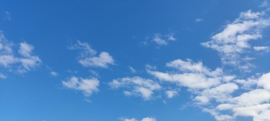 Blue sky background with white clouds, rain clouds on sunny summer or spring day.