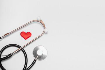 A red heart and a stethoscope or phonendoscope on a white background with a place for the text: cardiologist's day, international Day of Medicine, blood donor, crop. Health and Medical concept