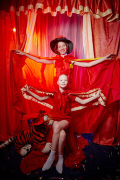 Family During A Stylized Theatrical Circus Photo Shoot In A Beautiful Red Location. Models Mother And Daughter Posing On Stage With Curtain