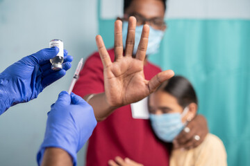 Selective focus on coronavirus vaccination bottle - Concept of Parents vaccine hesitancy for children, showing by saying no or stop gesture to vaccine with hand at hospital. - obrazy, fototapety, plakaty