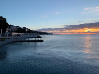 Dawn, the sun behind the clouds, a man is swimming in the sea