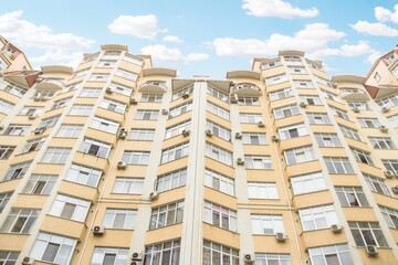 Fototapeta premium Fragment of Modern residential apartment with flat buildings exterior. Detail of New luxury house and home complex. Part of City Real estate property and condo architecture. Copy space. Blue sky