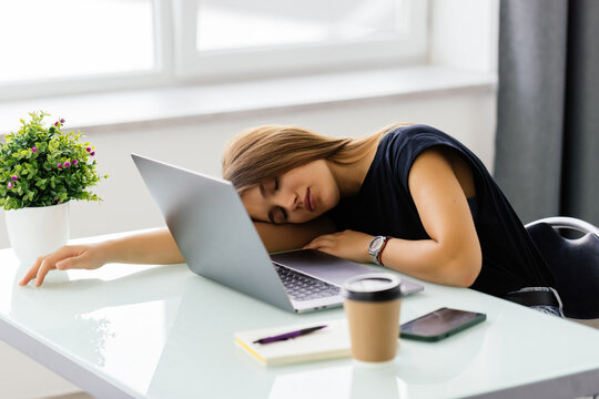 Tired businesswoman sleeping on the desk, in front of the laptop screen.