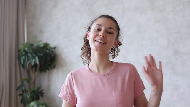 Online yoga training with skilled practitioner. Positive woman in pink t-shirt greets followers holding hands spbi in namaste mudra at home camera view 4k video
