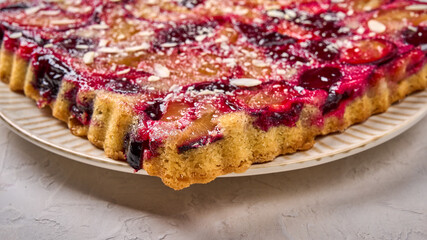 Macro panoramic orientation pie or tart with plums on plate on light wooden background. Selective focus