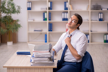 Young male employee and a lot of work in the office