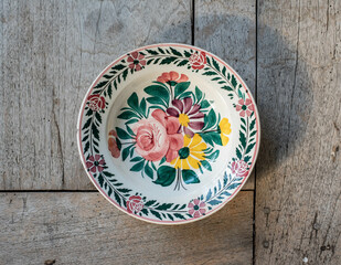 Obraz na płótnie Canvas Vintage porcelain plate with rose flower pattern - on a rustic wooden table