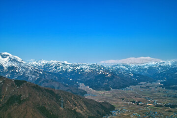 Fototapeta 春の雪残る山と麓の集落 obraz