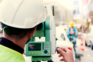 Engineer surveyor working with theodolite at road construction site