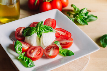 Caprese salad with mozarella cheese,tomatoes and basil on a white plate