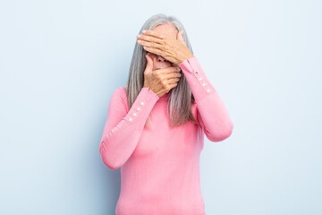 middle age gray hair woman covering face with both hands saying no to the camera! refusing pictures...
