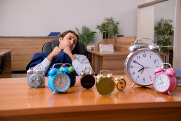 Young male employee sleeping in the office in time management co