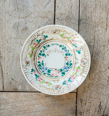 Vintage fayance wall plate with flowers on a rustic wooden table