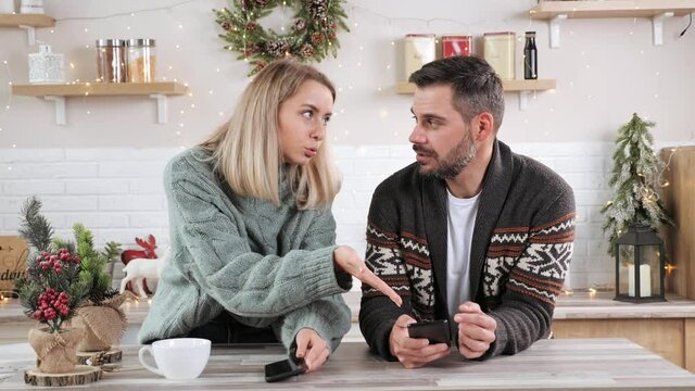 Sadness young wife having quarrel with husband in the kitchen upset couple having relationship problem conflict in Christmas eve. Couple arguing on New Years eve. Adult man and woman are stressed.