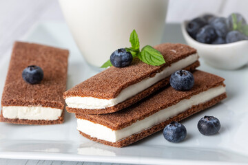 Chocolate biscuit with milk filling and berries on a plate. Chocolate-milk kids dessert. (Turkish dessert; sut dilimi)