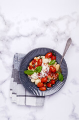 Gnocchi with tomatoes, red sauce, cheese and basil leaves