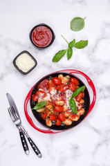 Gnocchi with tomatoes, red sauce, cheese and basil leaves