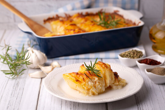 Potato gratin - graten (baked potatoes with cream and cheese) with rosemary and forks (Turkish name; Kremali patates)