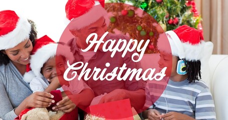 Composition of happy christmas text over smiling african american family wearing santa hats - Powered by Adobe