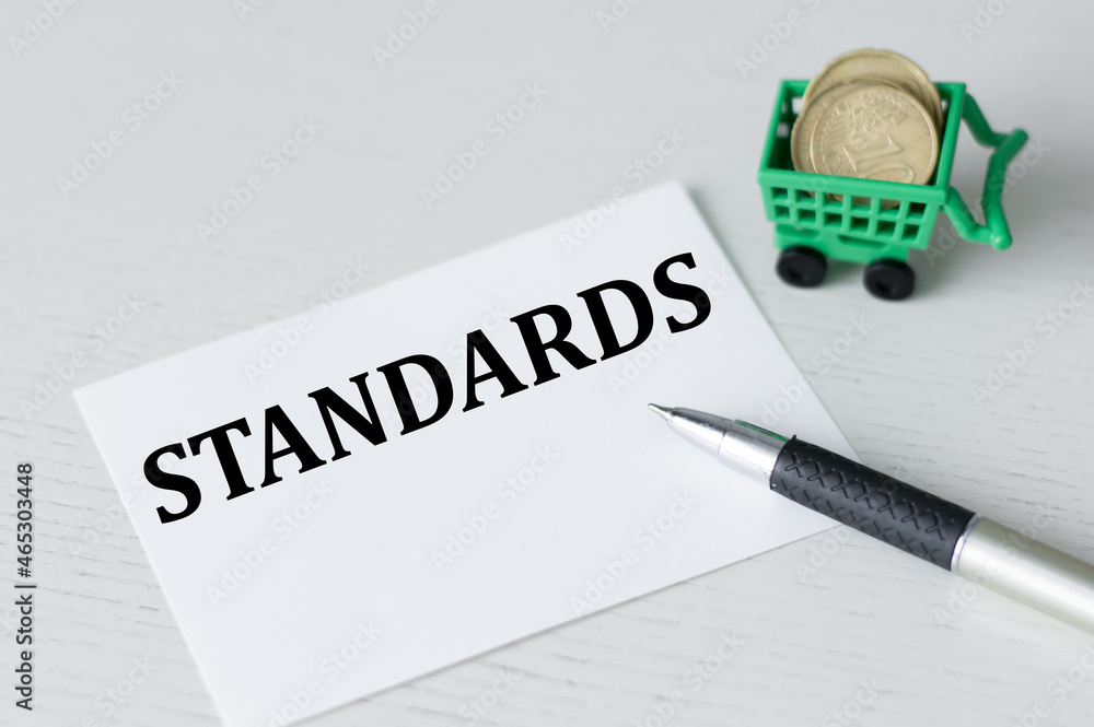 Poster card with text standards on a light table next to a pen and coins