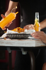 Man pouring spicy sauce on mexican snack nacho