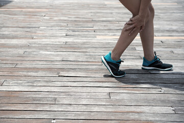 Unrecognizable woman in sports shoe touching leg while feeling muscle pain after jogging