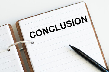 Conclusion text on a notebook with marker on a light background