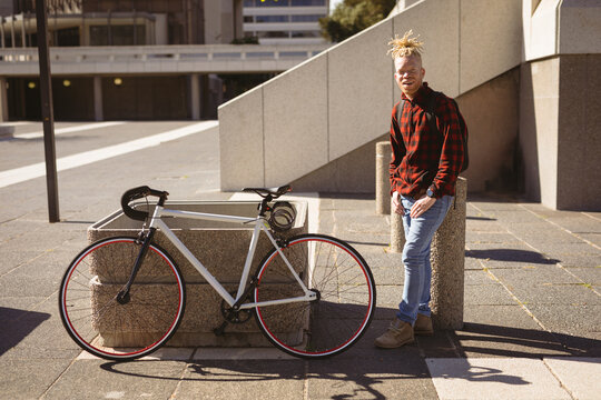 Portrait of smiling albino african american man with dreadlocks on street with bike