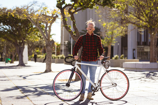 Portrait of smiling albino african american man with dreadlocks in park with bike