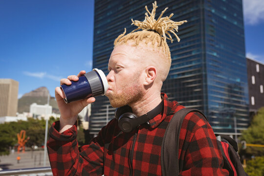 Albino african american man with dreadlocks drinking takeaway coffee - Powered by Adobe