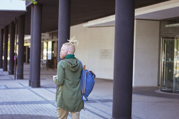 Thoughtful albino african american man with dreadlocks walking using smartphone