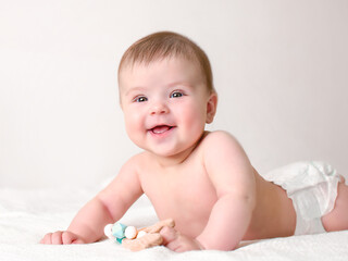 A charming little girl lies on a white blanket holding a toy in her hand