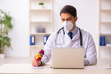 Young male doctor cardiologist working in the clinic during pand