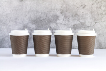 Four corrugated takeaway paper coffee cups with caps close-up