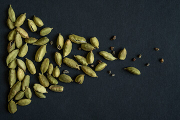 Close up photo of Cardamom pods and seeds pile on the matt black background. It is very popular in Indian and Sri Lanka cuisine.