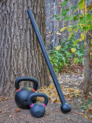 steel mace (or macebell) and iron kettlebells in a backyard, home functional fitness concept using unconventional equipment