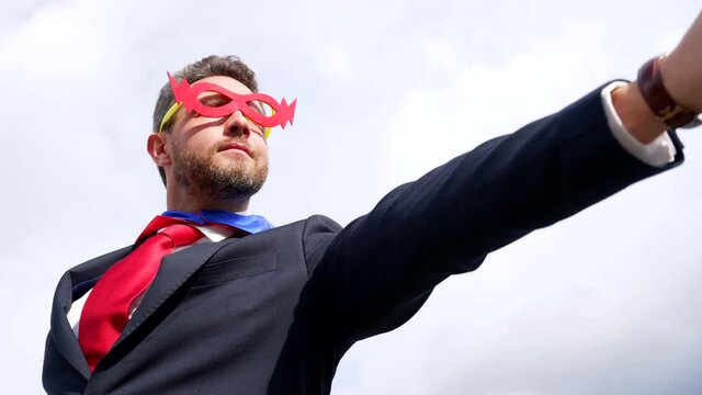 businessman in superhero suit with raised hand on sky background, business success
