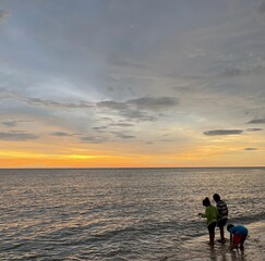 Fototapeta premium kids playing sea water during sunset by the beach