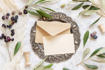 Blank card and envelope on table with olive tree branches