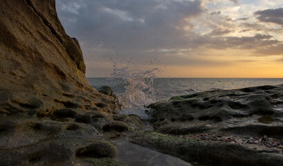 Russia. Republic of Dagestan. Sea surf splashes on the coastal rocks of the Caspian Sea against the background of the dawn sky on the embankment of the city of Makhachkala.
