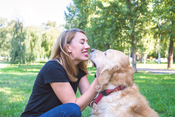 Happy young woman plays with her dog outdoors.