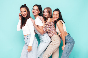 Four young beautiful smiling brunette hipster female in trendy summer clothes. Sexy carefree women posing near blue wall. Positive models having fun. Cheerful and happy