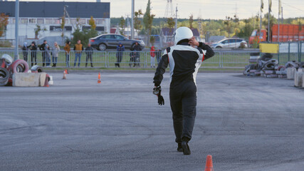 A racer in a sports uniform is walking on a race track. Selective focus.