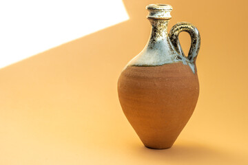 small clay ceramic vase with handle on a yellow background. dusty vase on window. home decoration, sunny background.handmade terracotta vase,orange color.