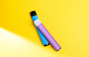 disposable electronic cigarettes with shadow on a yellow background with copy space. The concept of modern smoking, vaping and nicotine. top view.