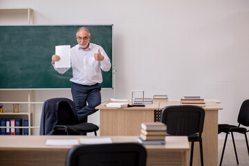 Old male teacher in front of blackboard